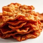 Beef Chips: A Tasty, High-Protein Snack Option 11 beef chipsA close-up image of crispy beef chips arranged on a plate, garnished with fresh herbs and served with a side of creamy dip, highlighting their savory and crunchy appe